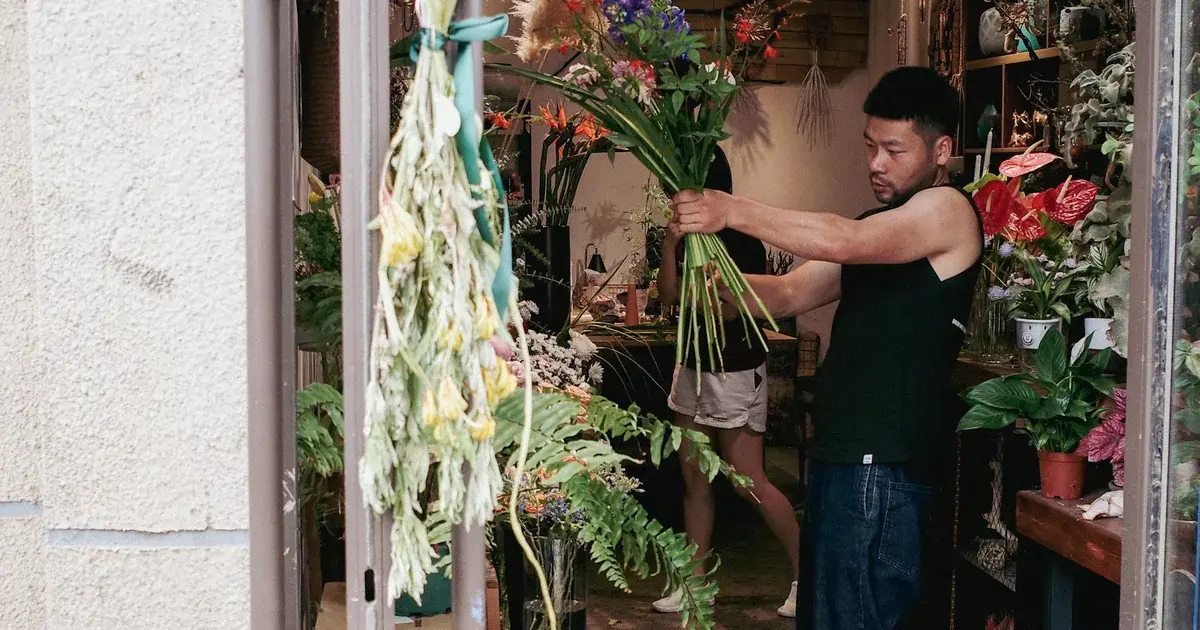 A florist gathering stems in the entrance to a flower shop